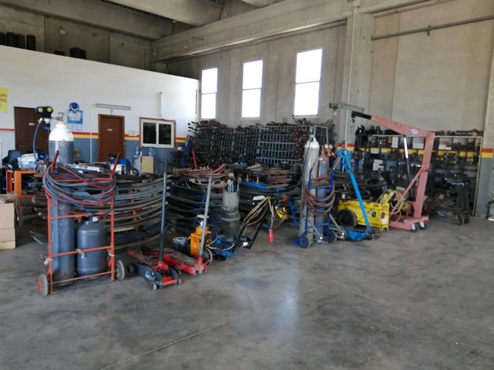 Interno dell'officina con le rastrelliere delle molle a balestra e i banchi di lavoro.